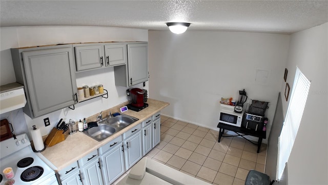 kitchen with white range oven, light tile patterned flooring, a textured ceiling, lofted ceiling, and sink