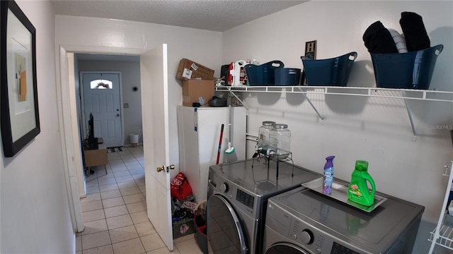 clothes washing area with a textured ceiling, light tile patterned floors, and washing machine and clothes dryer