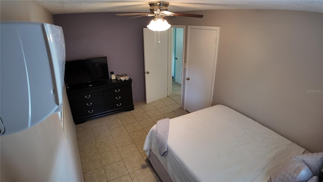 bedroom featuring ceiling fan, light tile patterned floors, and a textured ceiling