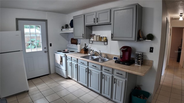 kitchen featuring light tile patterned floors, sink, white appliances, and gray cabinetry