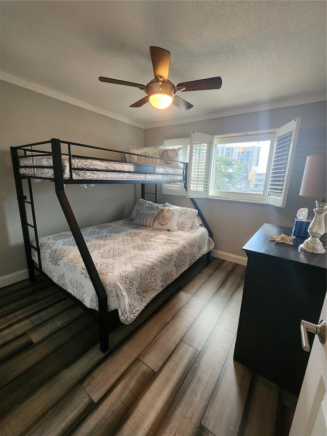 bedroom with crown molding, a textured ceiling, dark wood-type flooring, and ceiling fan