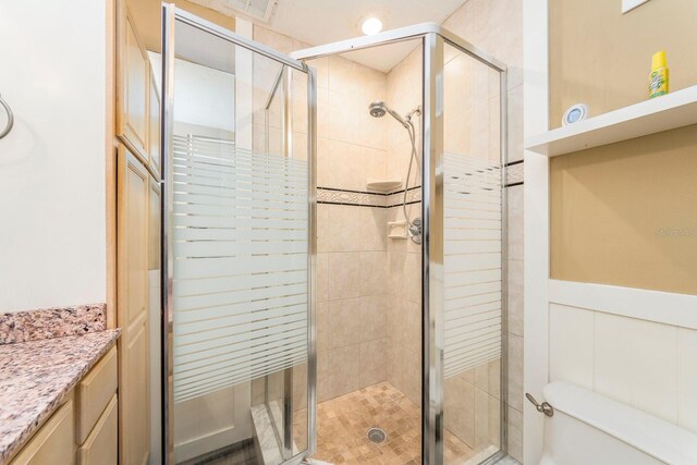 bathroom with toilet, an enclosed shower, and vanity