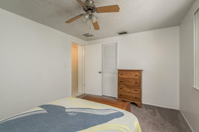 carpeted bedroom with a textured ceiling, ceiling fan, and a closet