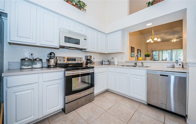 kitchen featuring stainless steel appliances, white cabinetry, a notable chandelier, light tile patterned floors, and sink