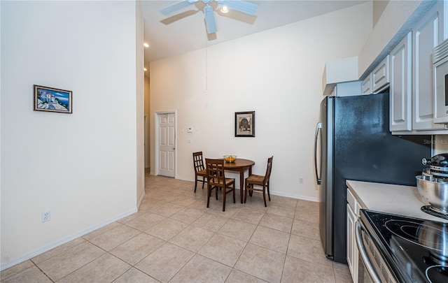 kitchen featuring electric stove, a towering ceiling, light tile patterned floors, gray cabinets, and ceiling fan