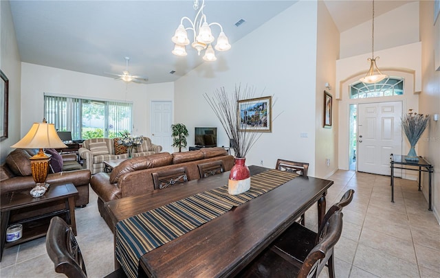 dining area featuring ceiling fan with notable chandelier, light tile patterned floors, and high vaulted ceiling