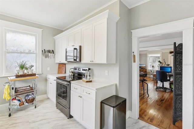 kitchen featuring white cabinets, appliances with stainless steel finishes, ornamental molding, and light hardwood / wood-style flooring