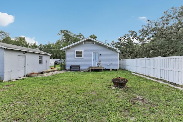 back of property with a fire pit and a yard