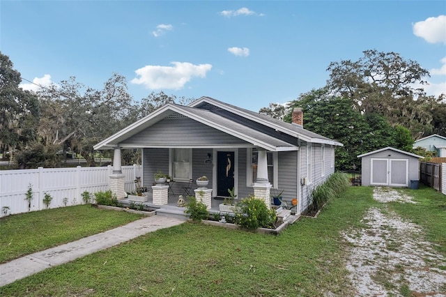 view of front of house with a storage shed, a porch, and a front lawn