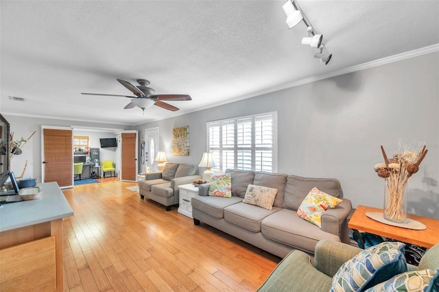 living room featuring track lighting, ornamental molding, a textured ceiling, light hardwood / wood-style floors, and ceiling fan