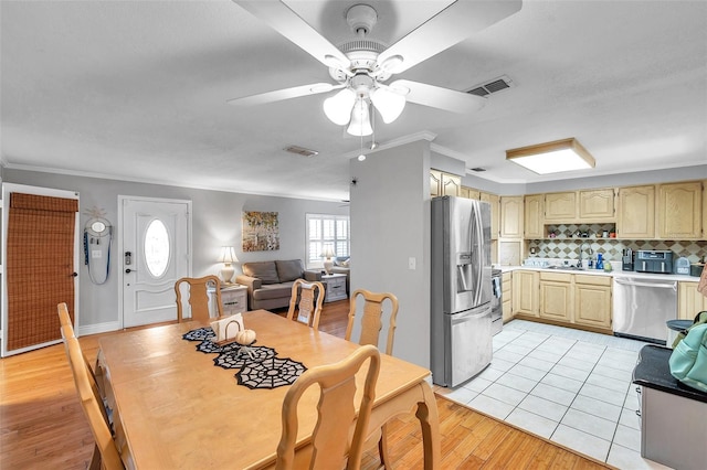 dining room with light hardwood / wood-style floors, ornamental molding, and ceiling fan