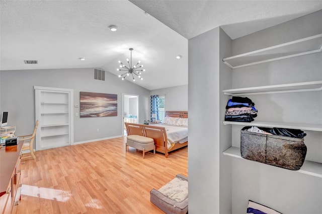 bedroom with an inviting chandelier, a textured ceiling, hardwood / wood-style flooring, and vaulted ceiling