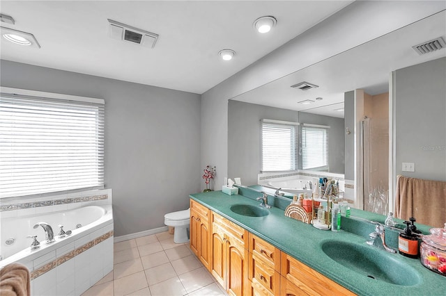 bathroom featuring vanity, toilet, a relaxing tiled tub, and tile patterned floors