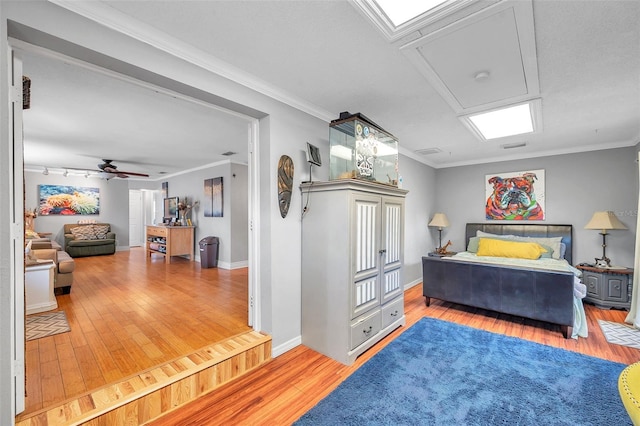 bedroom featuring ornamental molding, track lighting, wood-type flooring, and ceiling fan