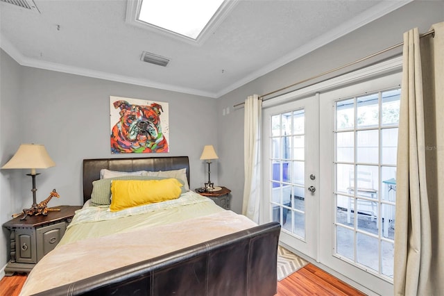 bedroom with french doors, a textured ceiling, light wood-type flooring, and crown molding