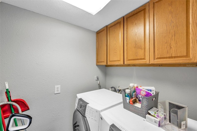 clothes washing area with cabinets, washer and dryer, and a textured ceiling