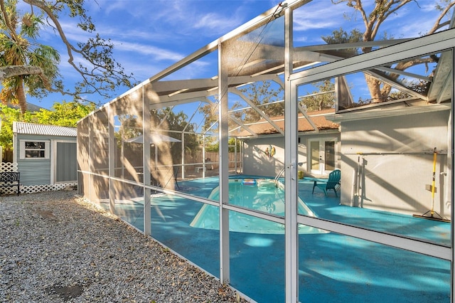 view of swimming pool featuring a patio, a storage unit, glass enclosure, and french doors