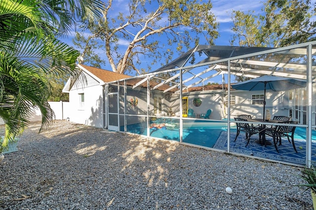 exterior space featuring a fenced in pool, a patio, and glass enclosure