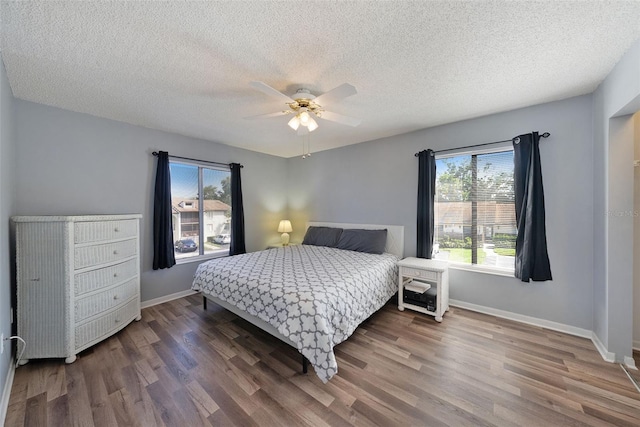 bedroom with hardwood / wood-style floors, ceiling fan, and a textured ceiling