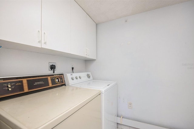 washroom featuring cabinets, a textured ceiling, and washer and dryer