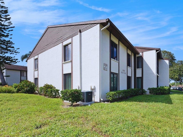 view of property exterior with a lawn and cooling unit