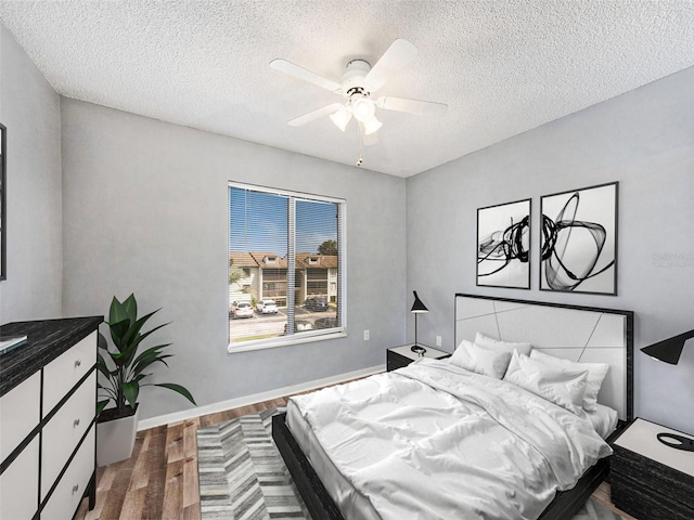 bedroom with ceiling fan, wood-type flooring, and a textured ceiling