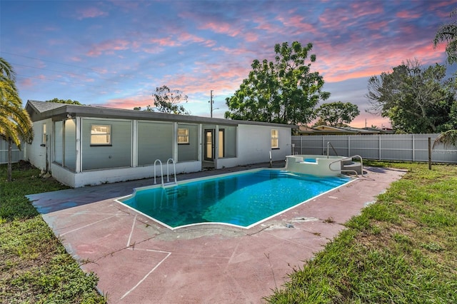 pool at dusk with a patio area