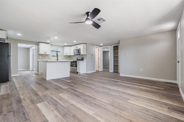 kitchen featuring ceiling fan, white cabinets, a textured ceiling, appliances with stainless steel finishes, and light wood-type flooring