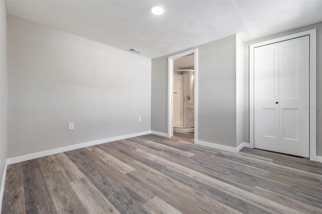 unfurnished bedroom with light hardwood / wood-style floors, ensuite bathroom, and a closet