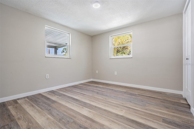 unfurnished room with hardwood / wood-style flooring and a textured ceiling