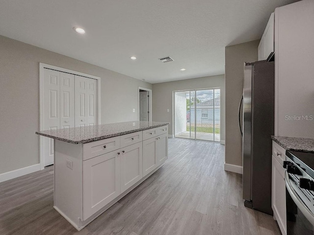 kitchen featuring light stone counters, light hardwood / wood-style flooring, white cabinets, and stainless steel appliances