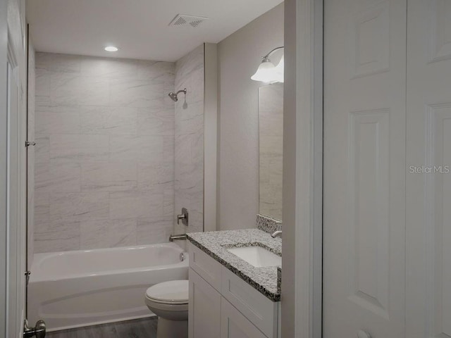 full bathroom with vanity, wood-type flooring, tiled shower / bath combo, and toilet