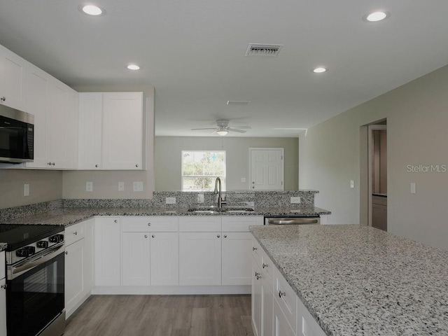 kitchen featuring light stone countertops, sink, stainless steel appliances, light hardwood / wood-style floors, and white cabinets