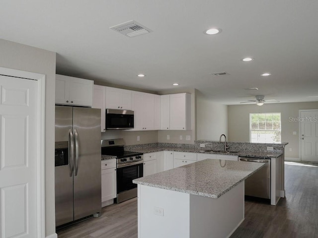 kitchen with dark hardwood / wood-style floors, a center island, sink, and appliances with stainless steel finishes