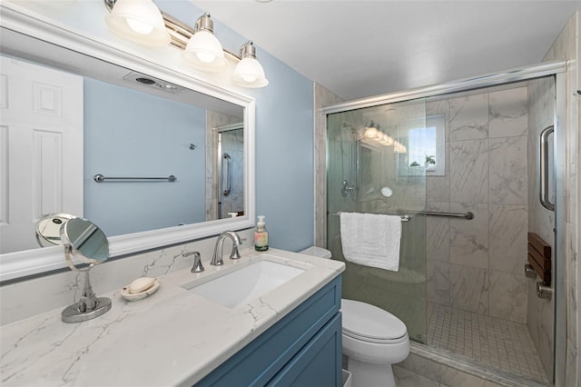 bathroom featuring a shower with door, vanity, and toilet