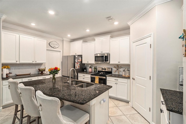 kitchen featuring appliances with stainless steel finishes, a center island with sink, decorative backsplash, and white cabinets