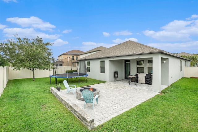 back of property featuring a trampoline, a patio area, and a yard