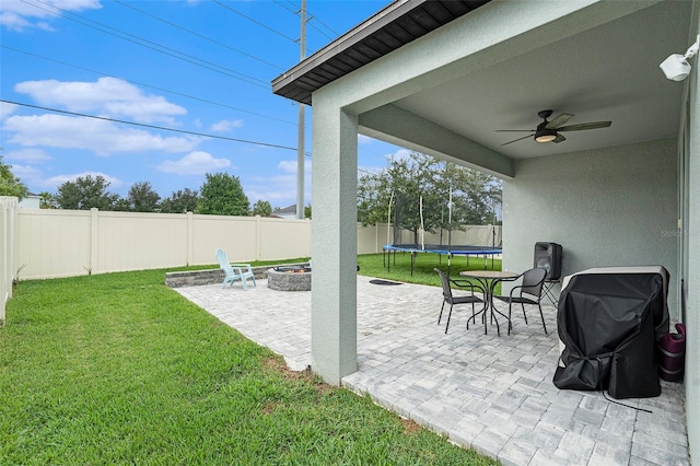 view of patio / terrace with ceiling fan, grilling area, a trampoline, and an outdoor fire pit