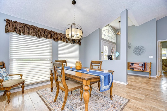 dining area featuring lofted ceiling, a chandelier, light hardwood / wood-style floors, and plenty of natural light