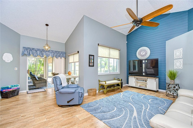 living room with high vaulted ceiling, a wealth of natural light, and light wood-type flooring