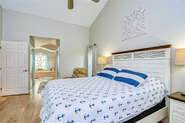 bedroom featuring light hardwood / wood-style flooring, ensuite bath, lofted ceiling, and ceiling fan