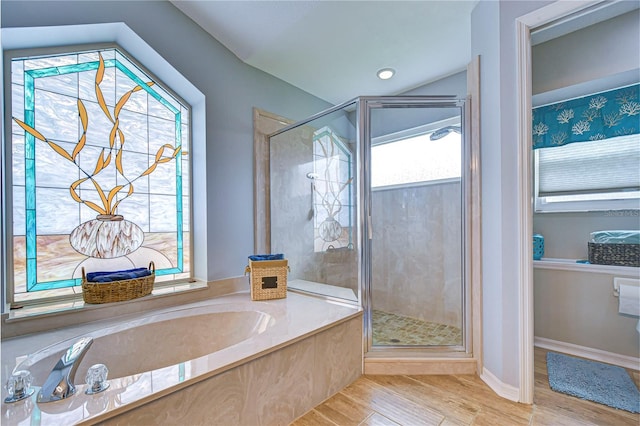 bathroom with plenty of natural light, shower with separate bathtub, and hardwood / wood-style floors