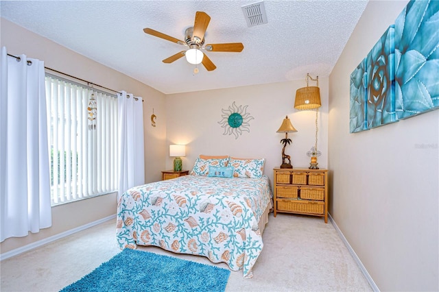 carpeted bedroom featuring ceiling fan and a textured ceiling