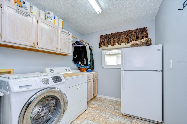 washroom with a textured ceiling, washing machine and dryer, and cabinets