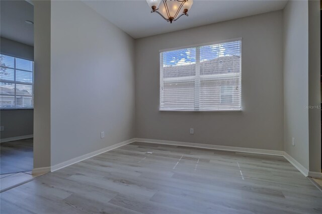 spare room featuring light wood-type flooring and a chandelier