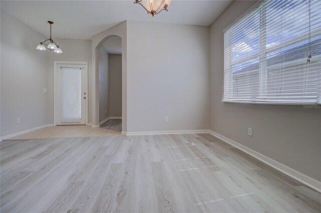 empty room with light wood-type flooring and a chandelier