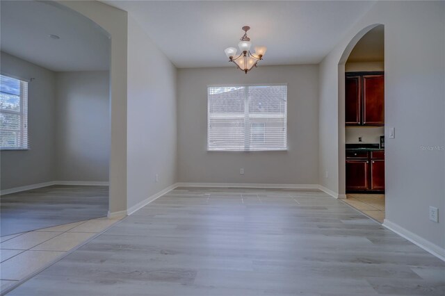 unfurnished dining area with light hardwood / wood-style flooring and a notable chandelier