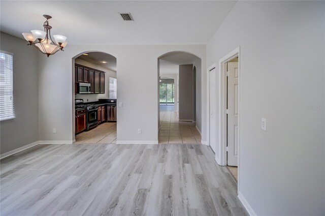 unfurnished dining area featuring light wood-type flooring, an inviting chandelier, and a wealth of natural light