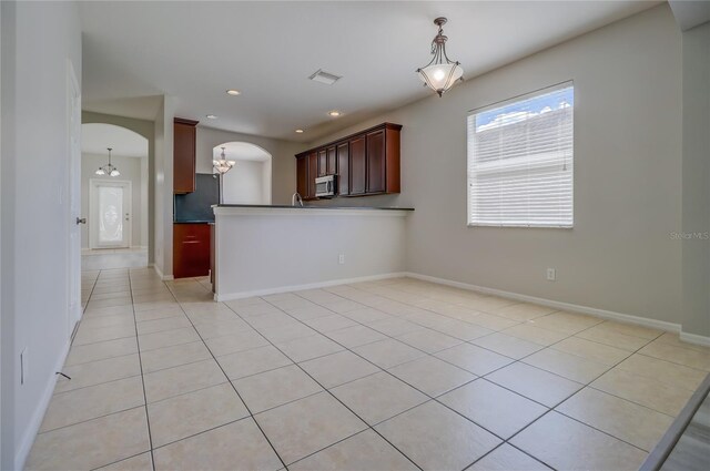 kitchen featuring a notable chandelier, kitchen peninsula, light tile patterned floors, and decorative light fixtures