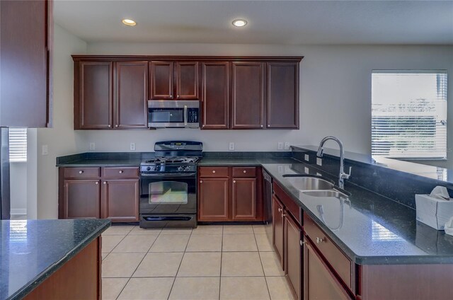 kitchen featuring dark stone countertops, sink, gas stove, and a healthy amount of sunlight